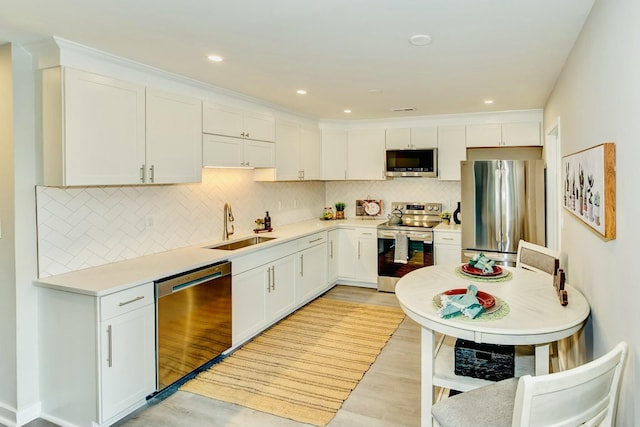 kitchen featuring tasteful backsplash, appliances with stainless steel finishes, white cabinets, and a sink