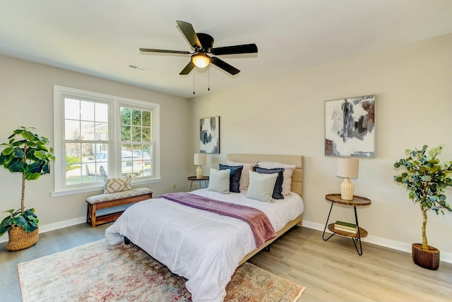 bedroom with light wood-style floors, visible vents, ceiling fan, and baseboards