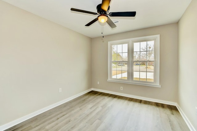 spare room featuring a ceiling fan, baseboards, visible vents, and wood finished floors