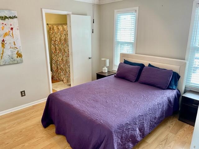 bedroom featuring light hardwood / wood-style floors, crown molding, and ensuite bathroom