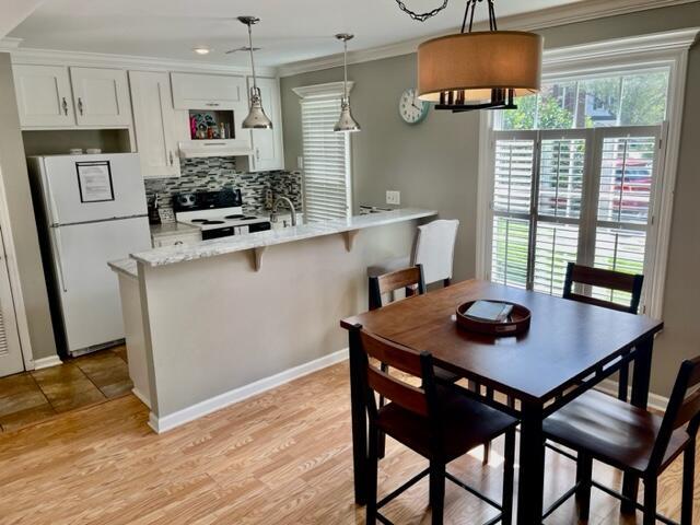 dining area featuring light wood-type flooring, crown molding, and sink