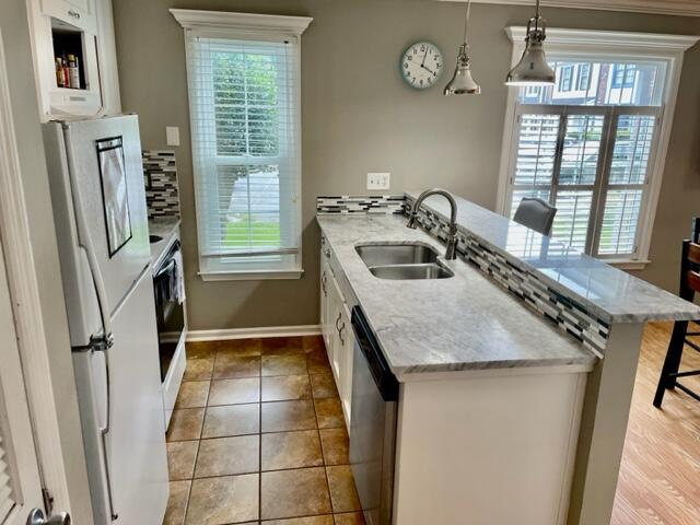 kitchen with white cabinetry, sink, hanging light fixtures, white refrigerator, and a kitchen bar