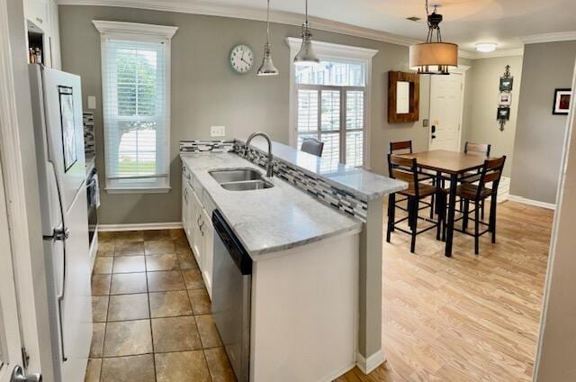 kitchen with pendant lighting, white cabinetry, a wealth of natural light, and stainless steel dishwasher