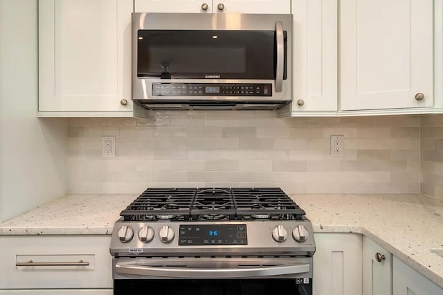 kitchen featuring backsplash, stainless steel appliances, white cabinetry, and light stone counters