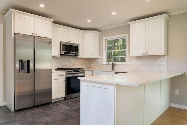 kitchen with kitchen peninsula, light stone counters, stainless steel appliances, sink, and white cabinets