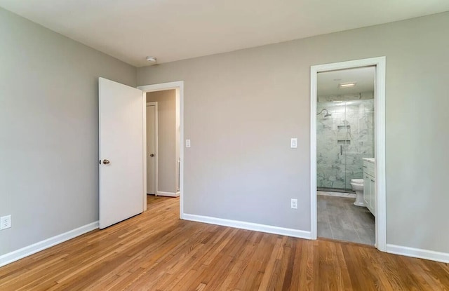 unfurnished bedroom featuring ensuite bathroom and light wood-type flooring