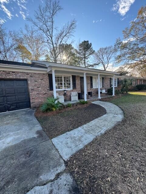 ranch-style house featuring covered porch, a garage, and a front lawn