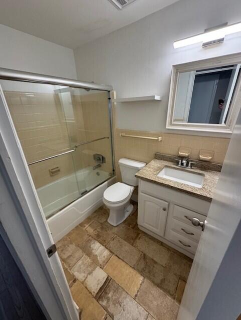 full bathroom featuring vanity, backsplash, toilet, and enclosed tub / shower combo