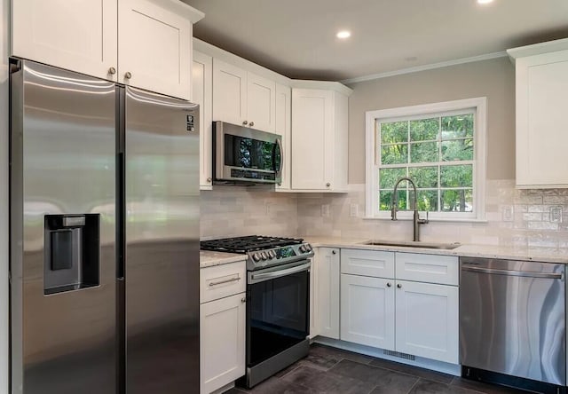 kitchen with backsplash, sink, light stone countertops, appliances with stainless steel finishes, and white cabinetry