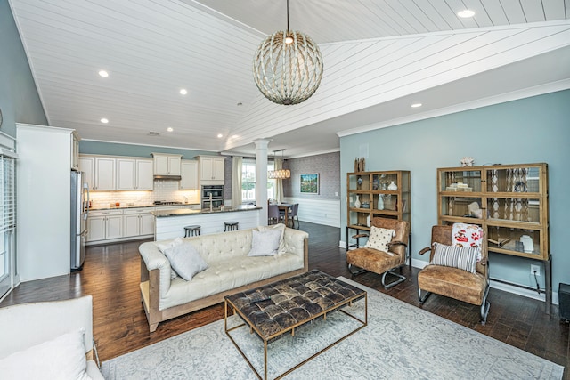 living room featuring ornate columns, dark wood-type flooring, and wooden ceiling