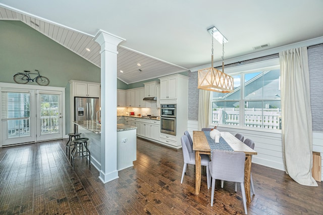 kitchen featuring appliances with stainless steel finishes, plenty of natural light, dark wood-type flooring, and decorative light fixtures