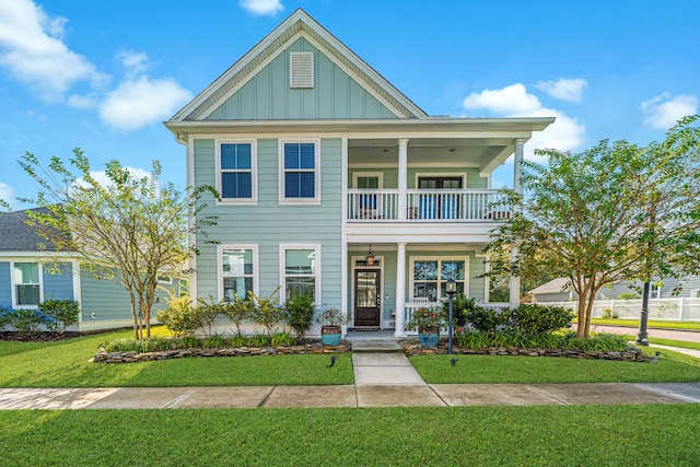 view of front of property with covered porch, a balcony, and a front yard