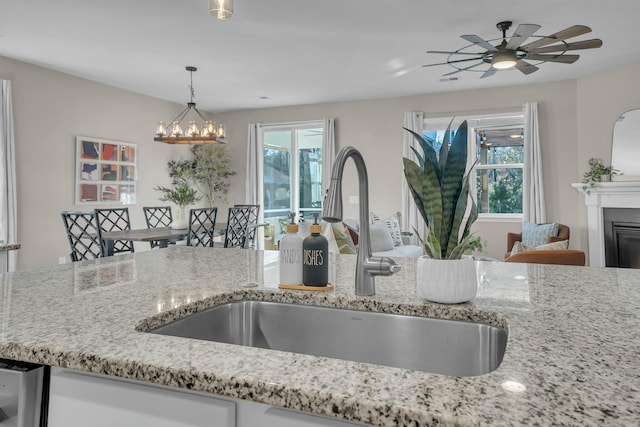 kitchen with a chandelier, sink, pendant lighting, and light stone counters