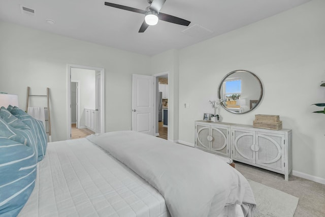 bedroom featuring light carpet, ceiling fan, and ensuite bath