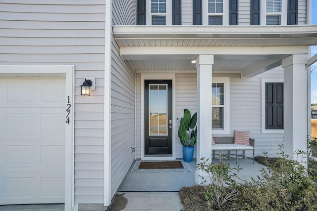 view of exterior entry featuring a porch and a garage