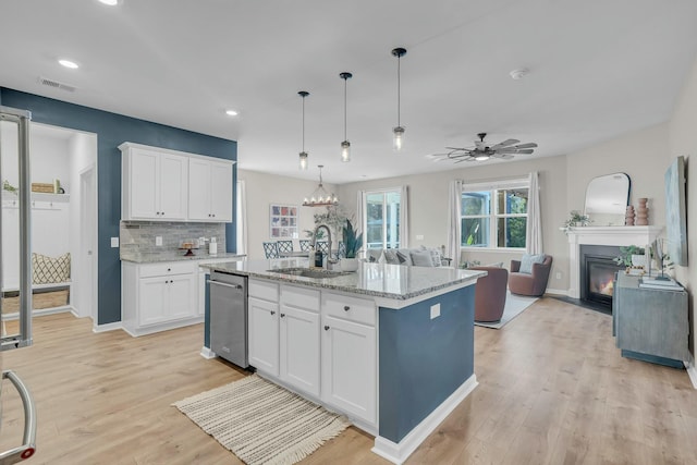 kitchen with a kitchen island with sink, sink, hanging light fixtures, and white cabinets