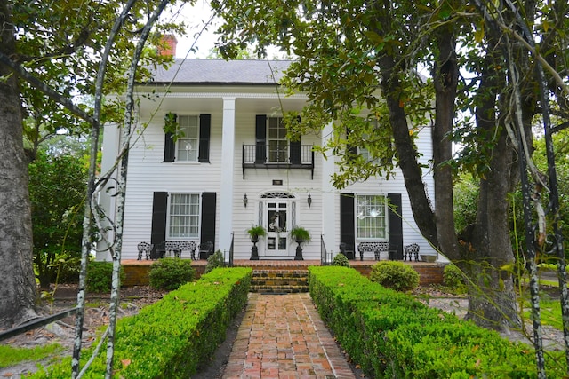 neoclassical home with a balcony and a chimney