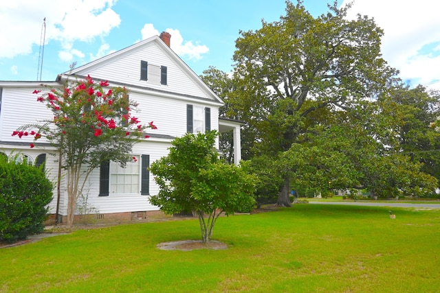 view of side of property featuring a lawn and a chimney