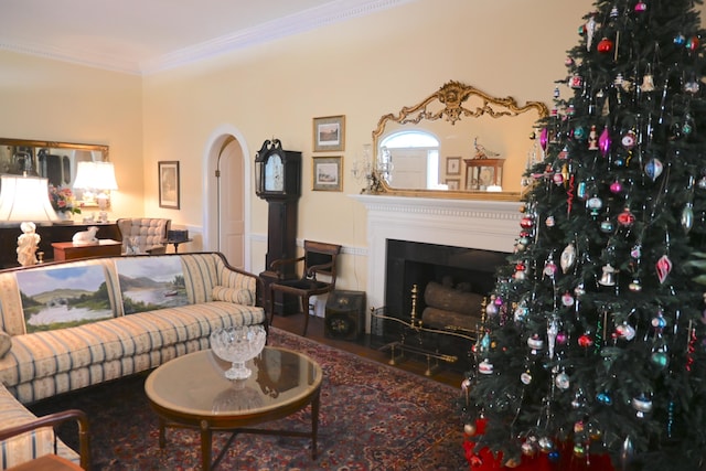 living room featuring arched walkways, a fireplace with flush hearth, crown molding, and wood finished floors