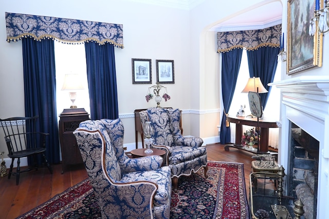 living area featuring wood finished floors, crown molding, a fireplace, and baseboards