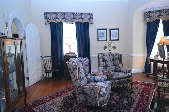 sitting room featuring wood finished floors, arched walkways, and baseboards
