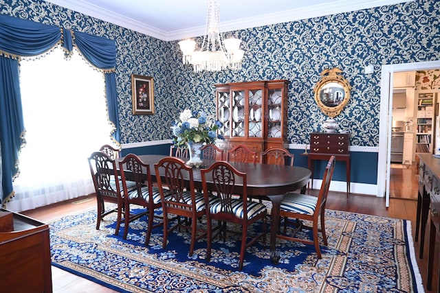 dining area featuring wallpapered walls, crown molding, a notable chandelier, and wood finished floors