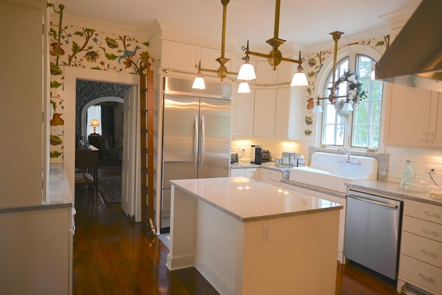kitchen with range hood, a kitchen island, a sink, stainless steel appliances, and white cabinetry