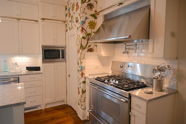 kitchen with tasteful backsplash, visible vents, ventilation hood, and stainless steel appliances