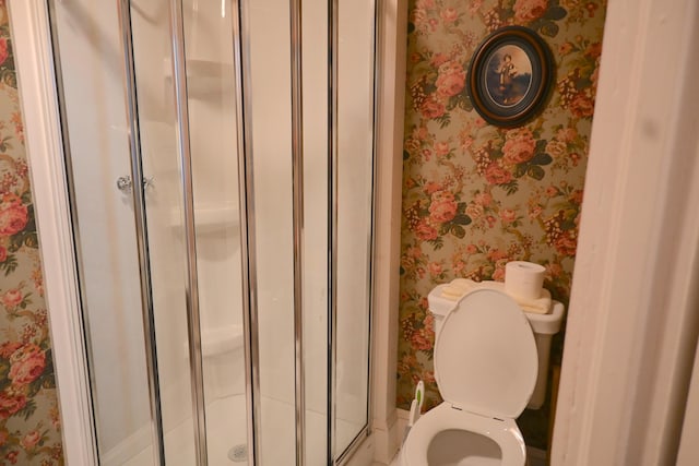 full bath with toilet, a stall shower, and wallpapered walls