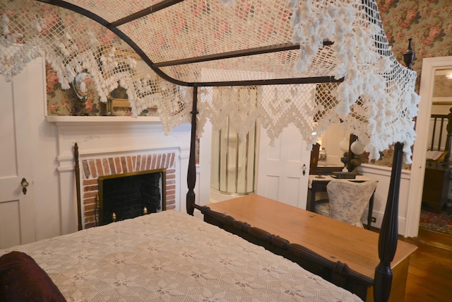 bedroom featuring a brick fireplace, brick ceiling, and wood finished floors