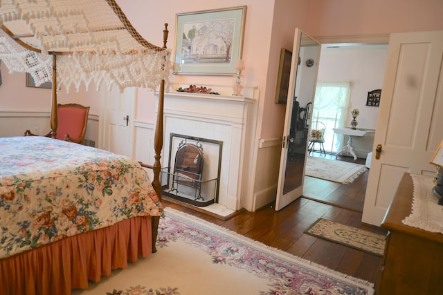 bedroom with a tile fireplace and hardwood / wood-style flooring