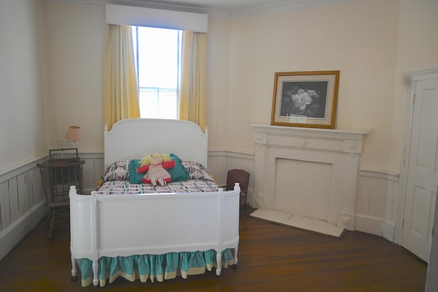 bedroom with crown molding, dark wood-style floors, and wainscoting