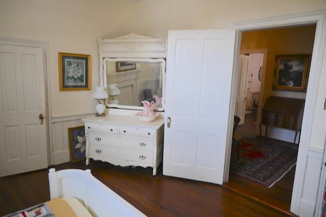 bedroom featuring a wainscoted wall and dark wood-style flooring