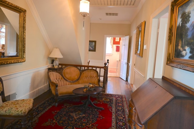 living area featuring visible vents, wainscoting, crown molding, and hardwood / wood-style flooring