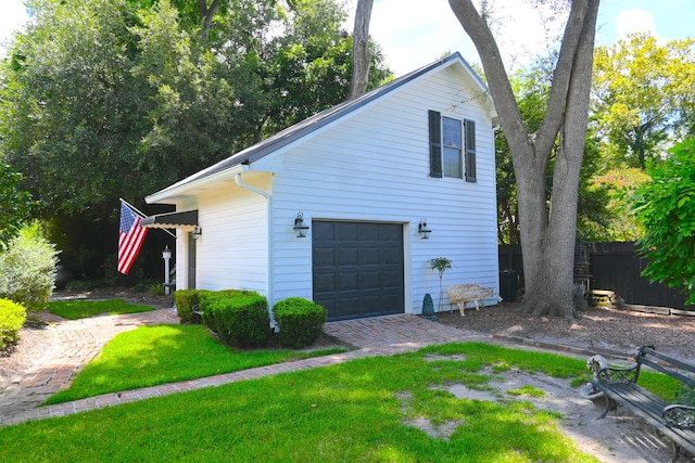 view of property exterior with a yard, a garage, and fence
