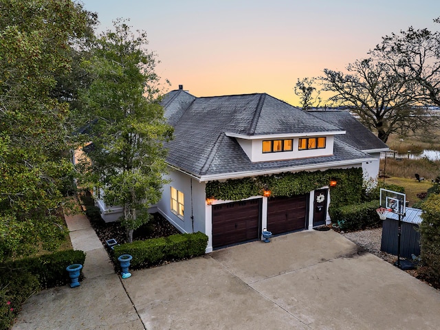 view of front facade with stucco siding, concrete driveway, a garage, and a shingled roof