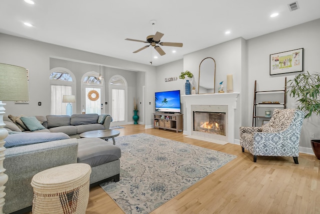 living room with recessed lighting, visible vents, and wood finished floors