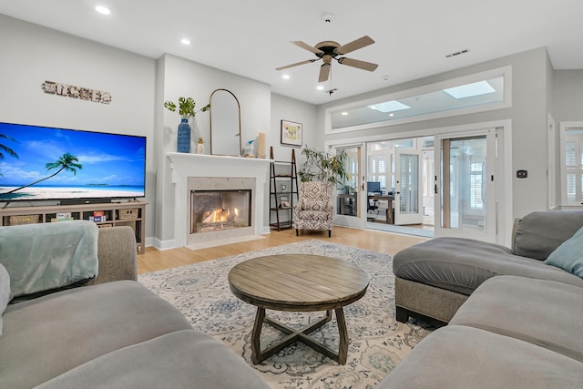 living room featuring visible vents, wood finished floors, recessed lighting, a skylight, and a fireplace