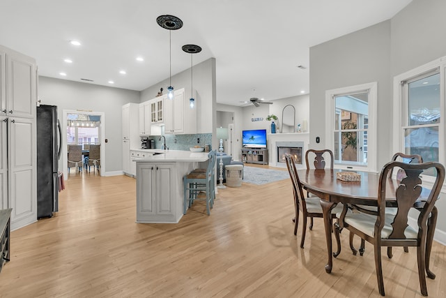 interior space featuring a peninsula, freestanding refrigerator, a sink, light countertops, and white cabinetry