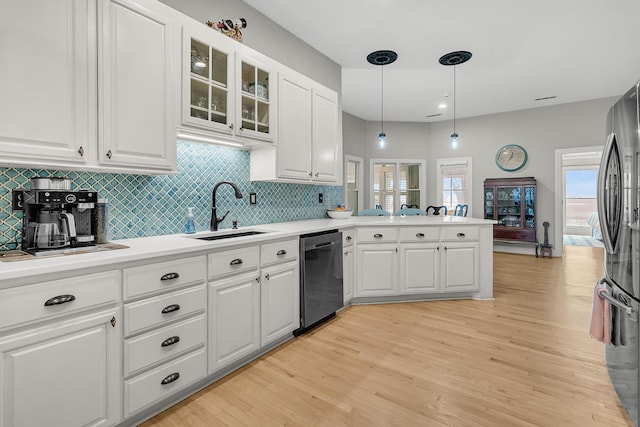 kitchen with light wood-type flooring, dishwashing machine, a peninsula, freestanding refrigerator, and a sink