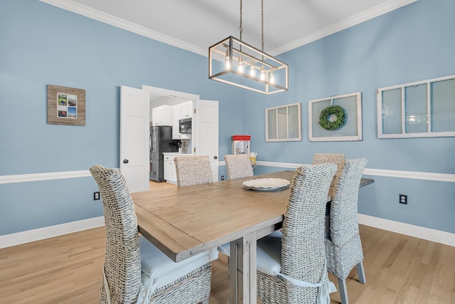 dining space featuring light wood-style flooring, baseboards, a notable chandelier, and ornamental molding