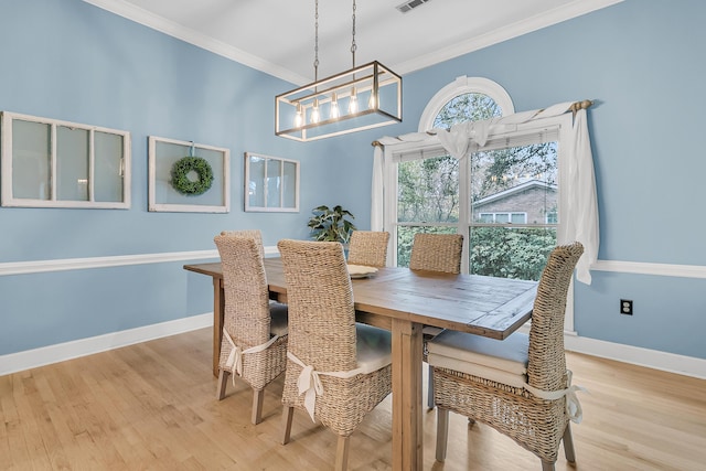 dining area featuring visible vents, baseboards, wood finished floors, and crown molding