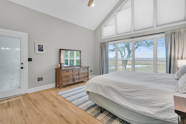 bedroom featuring light wood finished floors, baseboards, a water view, high vaulted ceiling, and a ceiling fan