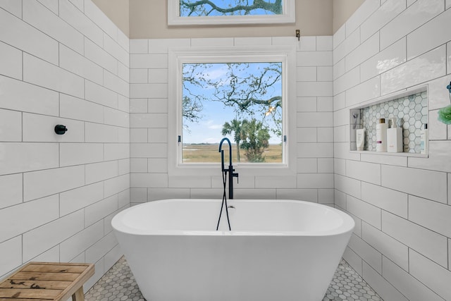 bathroom featuring tile patterned flooring, tile walls, and a freestanding tub