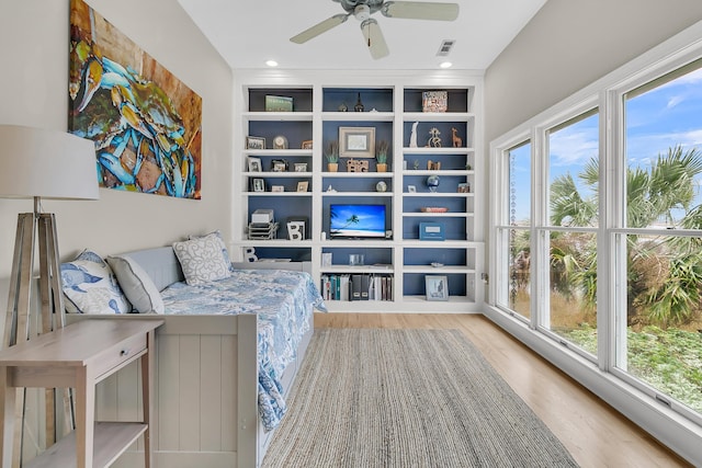 sitting room with plenty of natural light, a ceiling fan, visible vents, and wood finished floors