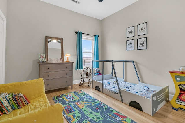 bedroom featuring visible vents, baseboards, and wood finished floors