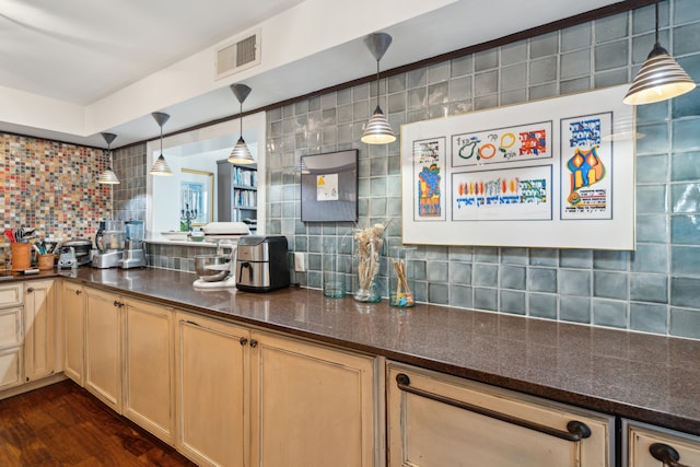 kitchen with hanging light fixtures, dark stone countertops, dark wood-type flooring, and tasteful backsplash