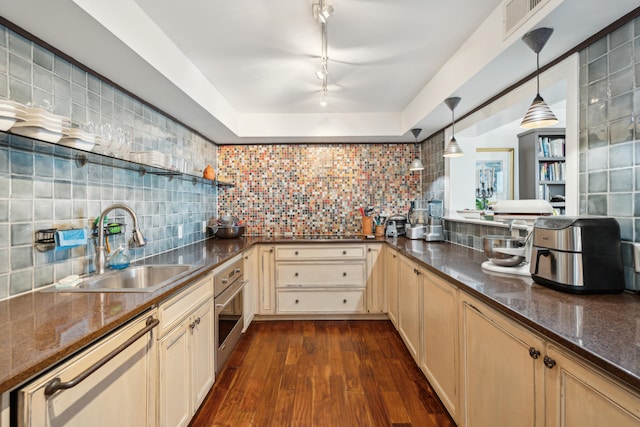 kitchen featuring pendant lighting, dark wood-type flooring, sink, backsplash, and appliances with stainless steel finishes