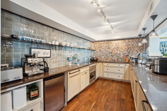 kitchen with sink, tasteful backsplash, decorative light fixtures, appliances with stainless steel finishes, and dark hardwood / wood-style floors