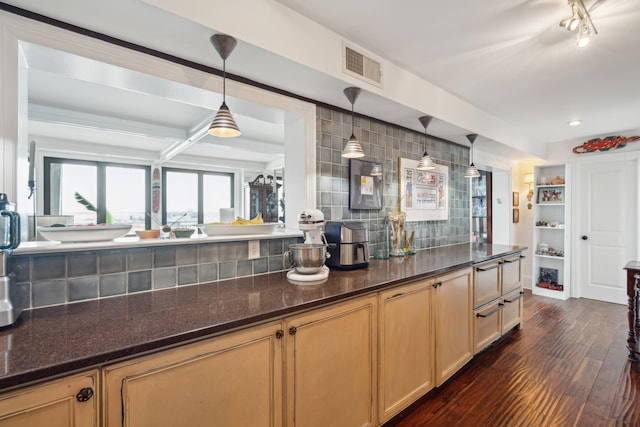 kitchen featuring hanging light fixtures, decorative backsplash, light brown cabinetry, dark stone counters, and dark hardwood / wood-style floors